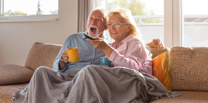 Rentnerpaerchen sitzt glücklich auf dem Sofa