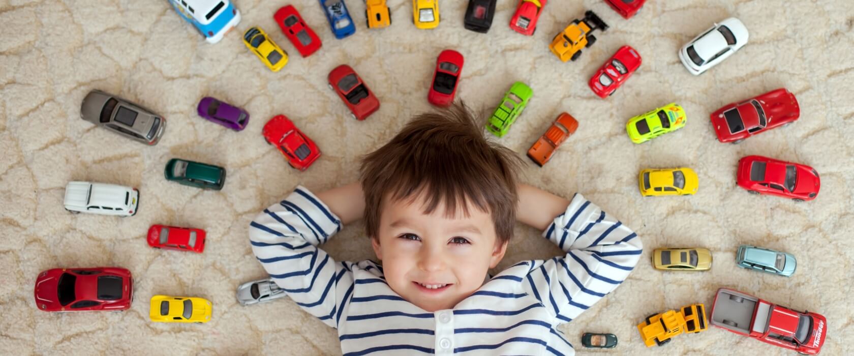 Junge liegt in vielen Spielzeugautos