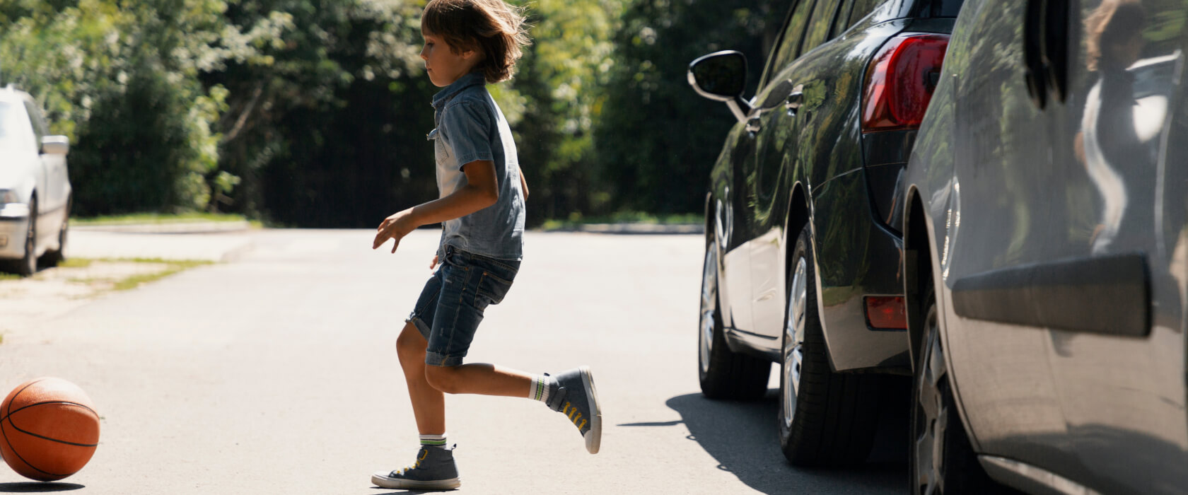 Junge rennt zwischen parkenden Autos durch