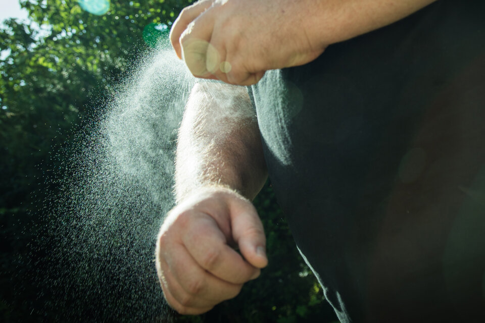 Arm wird mit Mückenspray besprüht