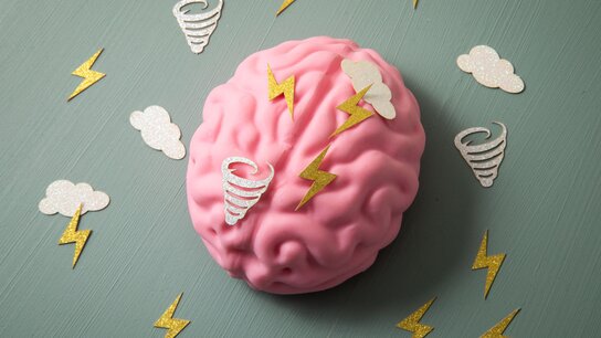 Ein gemaltes rosanes Gehirn, um das kleine, weiße Blitze, Wolken und Tornados rum fliegen.