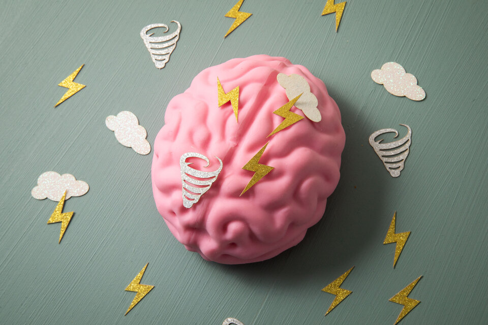 Ein gemaltes rosanes Gehirn, um das kleine, weiße Blitze, Wolken und Tornados rum fliegen.