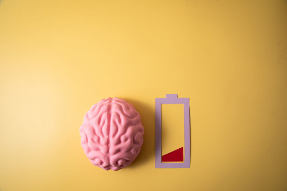 Comicansicht von einem Gehirn und einen fast leeren Akkuanzeige auf gelben Hintergrund.