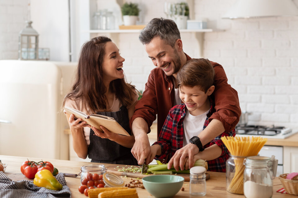 Familie kocht zusammen in einer modernen Küche, während sie gemeinsam an einem Rezept arbeiten und viel Spaß haben.