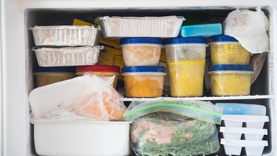 Gefrierfach mit verschiedenen Behältern, gefrorenem Gemüse, und Portionen in Aufbewahrungsboxen.