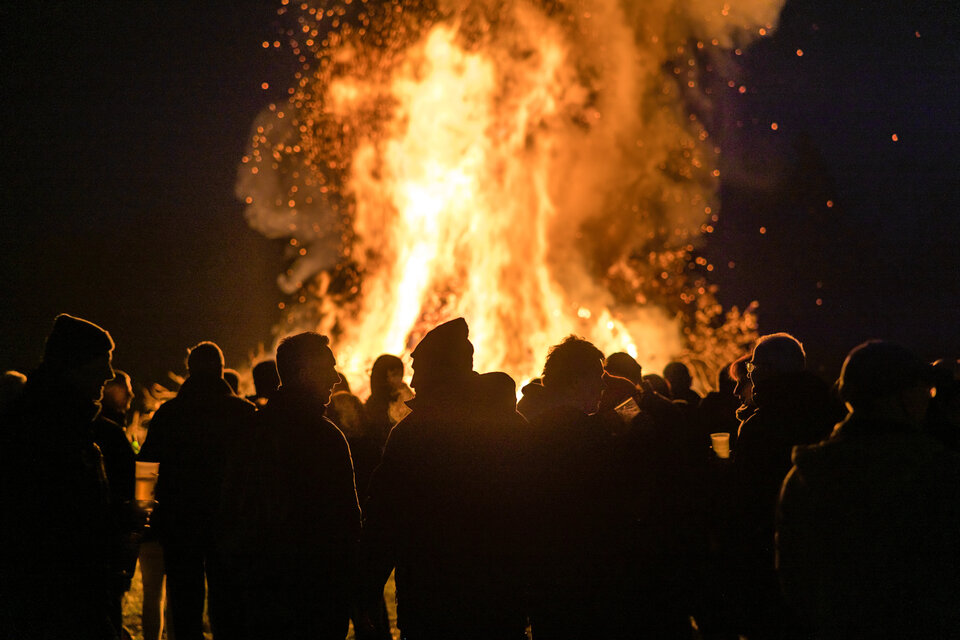 Ein Osterfeuer bei Nach vor dem viele Personen stehen und sich unterhalten.
