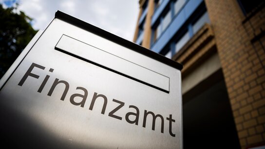 Briefkasten mit der Aufschrift Finanzamt vor einem Bürogebäude
