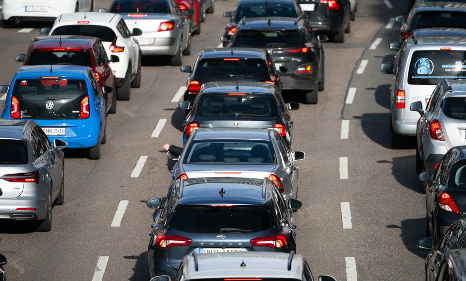 Stau auf einer mehrspurigen Straße mit verschiedenen Fahrzeugen, darunter Limousinen und Kleinwagen.