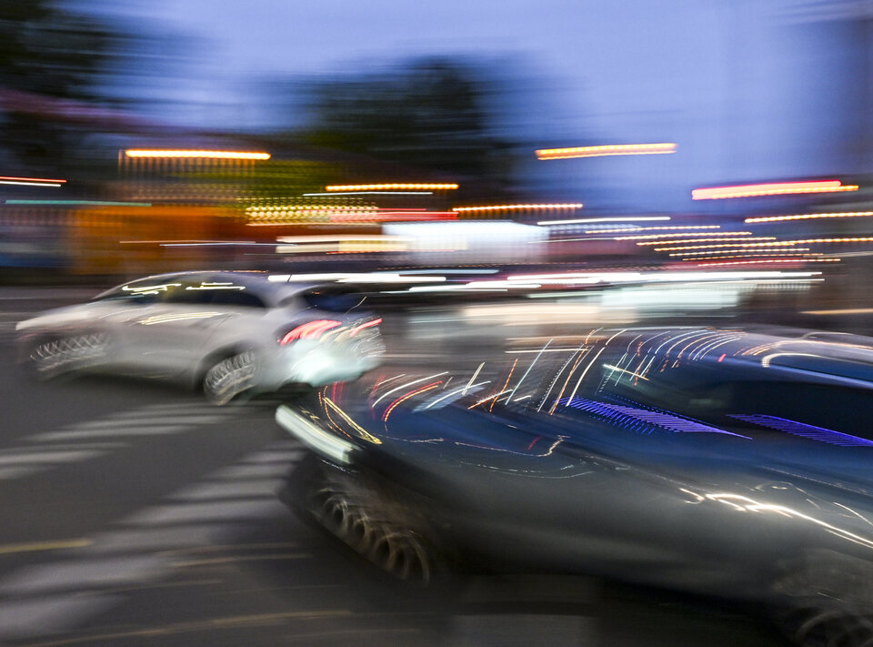 Ein unscharfes Bild von zwei Auto, die im Halbdunkeln nebeneinander abbiegen.