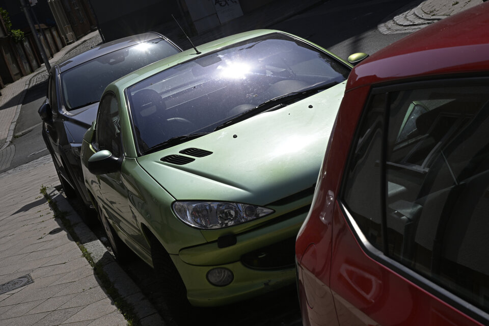 Drei Autos stehen an einer Straße in der Sonne.