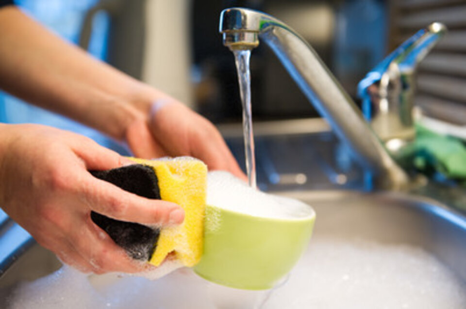 Tasse wird mit Schwamm abgewaschen