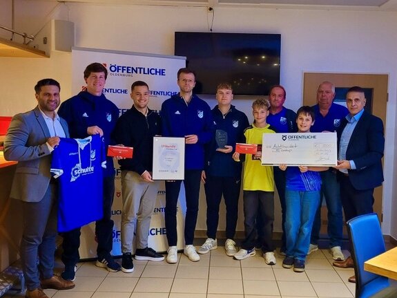 Gruppenszene mit Sportvereinsmitgliedern, die Auszeichnungen und ein großes Schecksymbol halten, um Erfolg zu feiern.