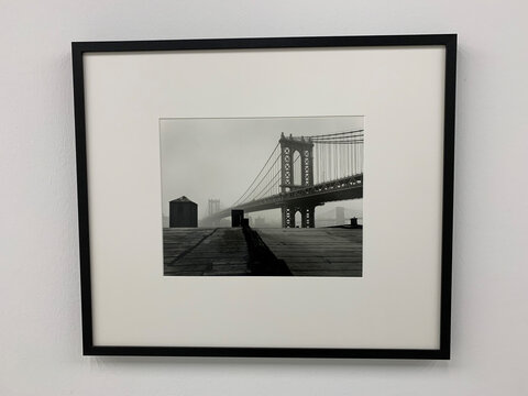 Schwarzweißaufnahme der Manhattan Bridge, umgeben von Nebel, mit einem grauen Dach im Vordergrund.