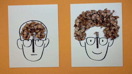 Kunstwerke zeigen zwei gezeichnete Gesichter mit unterschiedlichen Frisuren aus Bleistiftspänen auf oranger Hintergrund.