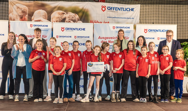 Gruppenzusammenkunft von Kindern in roten T-Shirts auf einer Bühne, die für ihre Leistungen ausgezeichnet werden.