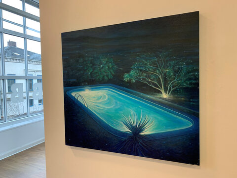 Ein beleuchteter Swimmingpool nachts, umgeben von Bäumen und Pflanzen, mit einem klaren, blauen Wasser.