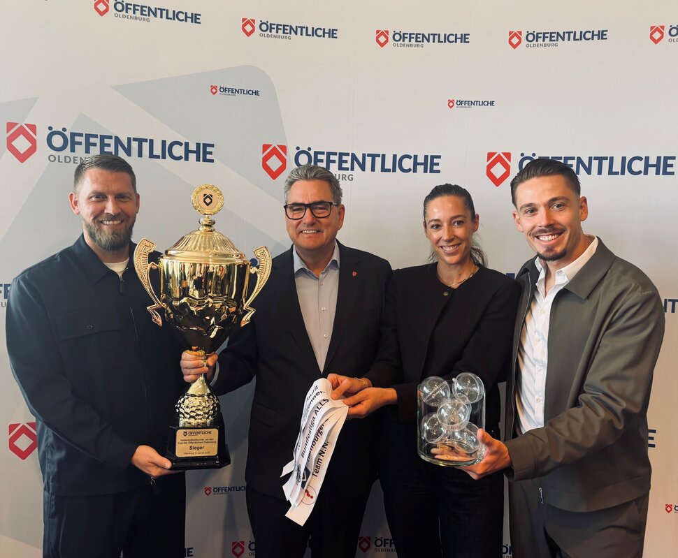 Aaron Hunt (ehemaliger Fußballer und Jürgen Müllender (Vorstandsvorsitzender der Öffentliche Oldenburg) halten einen Pokal, rechts daneben stehen Carina und Fabian Burdenksi