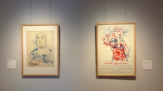 Zwei gerahmte Kunstwerke an einer Wand: links ein Porträt, rechts eine charakteristische Figur in lebendigen Farben.