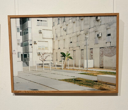 Szene einer urbanen Umgebung mit grauen Wohngebäuden, einem kleinen Baum, einem Zaun und Gehweg.