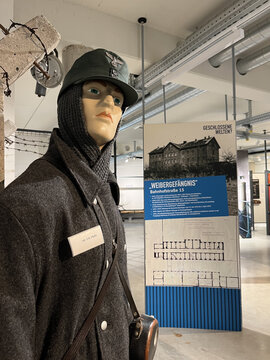 Schaufensterpuppe in uniform mit Mütze, steht neben einer Informationswand über das Weibergefangnis.