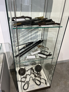 Historische Gefängnisgeräte und Handfesseln in einer Glasvitrine ausgestellt.