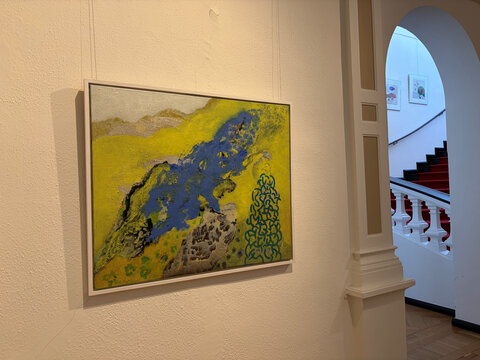 Abstraktes Gemälde mit blauen und gelben Farbtönen, hängend an einer weißen Wand in einem Ausstellungsraum.
