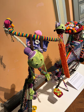 Bunt dekoriertes Fahrrad mit gehäkelten Figuren und bunten Garnen, das kreativ gestaltet ist.