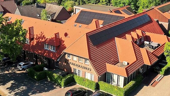Dächer mit roten Ziegeln und grüner Baumlandschaft im Hintergrund, mehrere Gebäude, darunter das Gasthaus Zum Zollhaus.