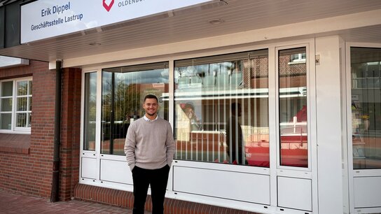 Mann steht vor der Geschäftsstelle "ÖFFENTLICHE" in Oldenburg, mit einem Schild und großen Fenstern im Hintergrund.