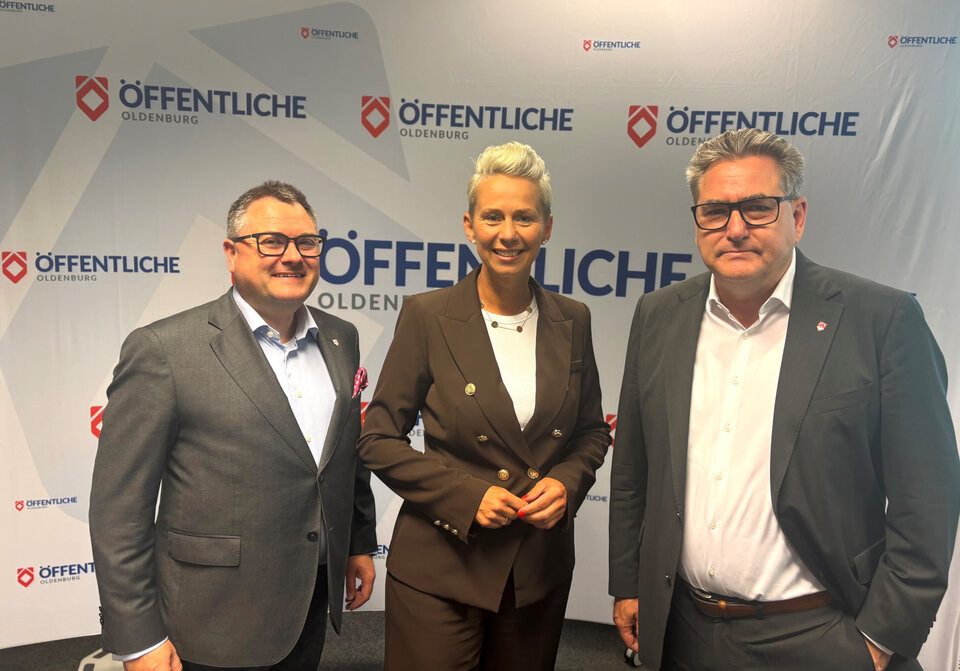 Ralf Kunze, Silvia Breher und Jürgen Müllender stehen vor einer Werbebande mit Logos der Öffentliche Oldenburg