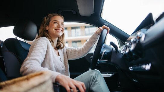 Lächelnde Frau fährt mit einem Auto.